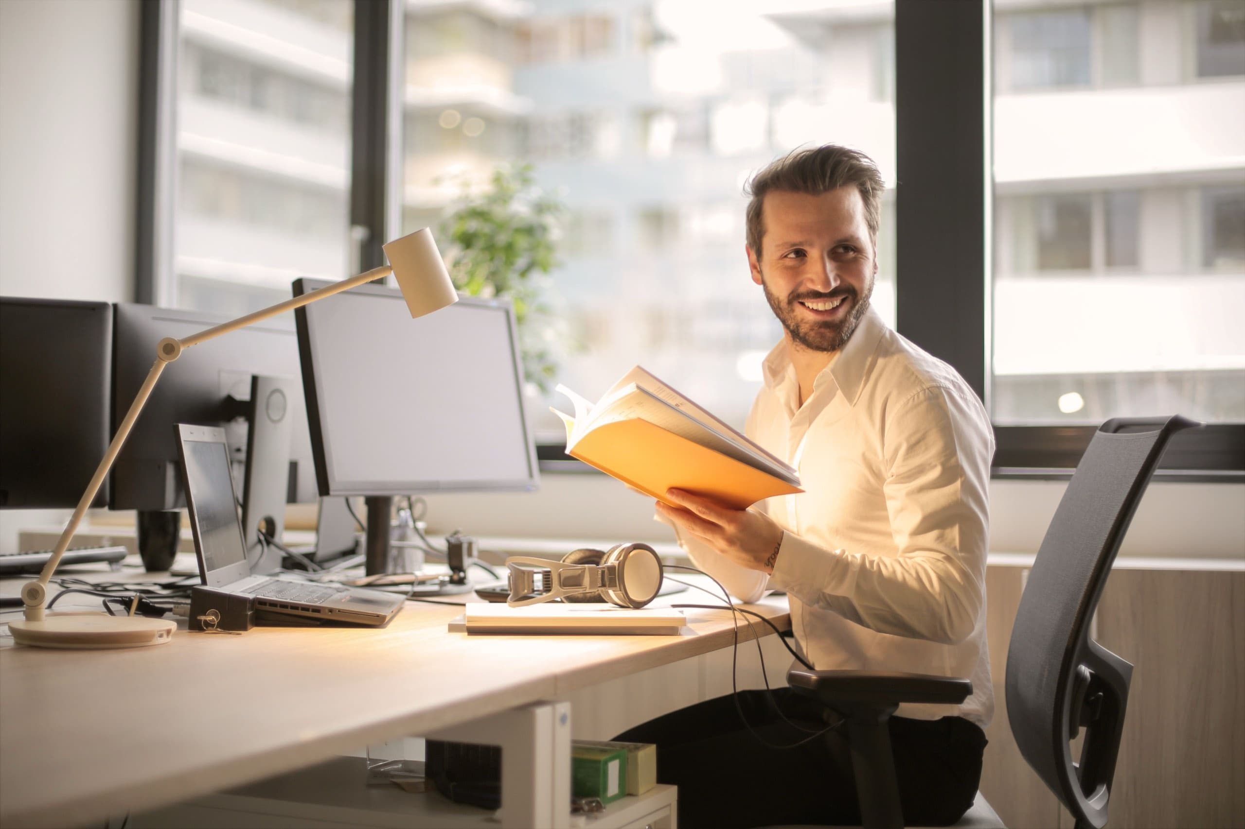 Beamter sitzt lächelnd mit Unterlagen am Schreibtisch im Büro